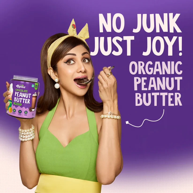 Woman holding an Alpino organic peanut butter jar in front of a purple promo