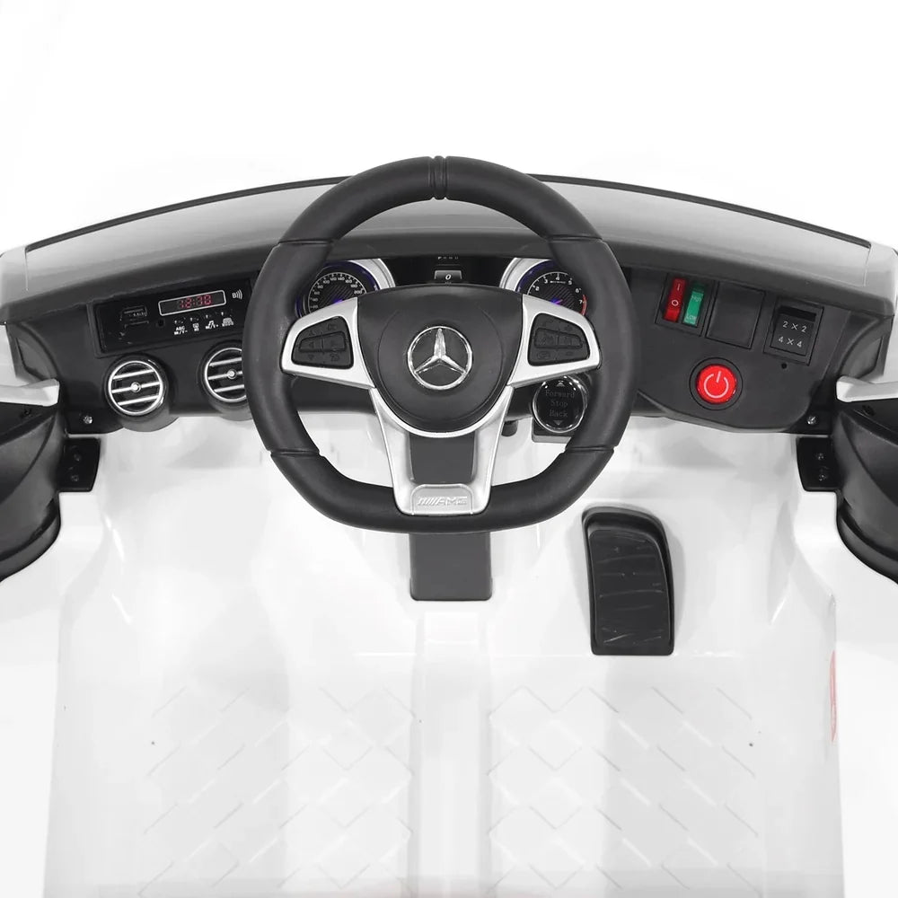 Interior of white Mercedes-Benz AMG ride-on car with steering wheel and dashboard buttons