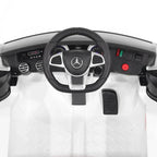 Interior of white Mercedes-Benz AMG ride-on car with steering wheel and dashboard buttons