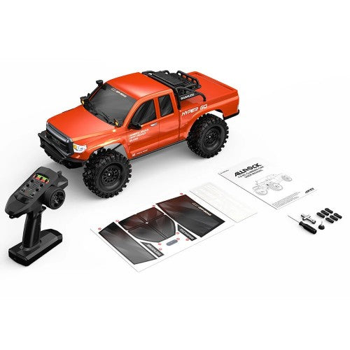 Orange RC crawler truck kit with remote controller, decals, and accessory parts