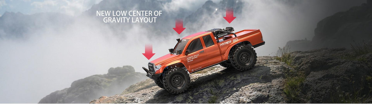 Orange RC rock crawler truck on rocky slope with suspension arrows
