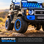 Front wheels of black kids ride-on jeep with gripped tires and glowing headlight LEDs